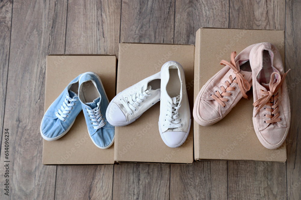 Cardboard boxes with stylish sneakers on light wooden background