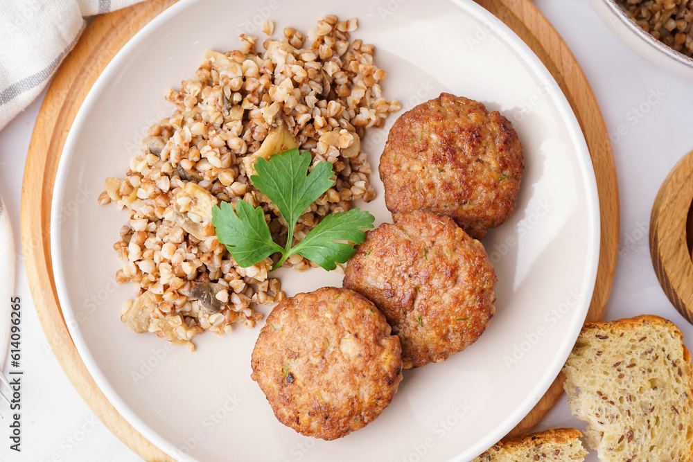 Cutlets with buckwheat, mushrooms and parsley on white table in kitchen