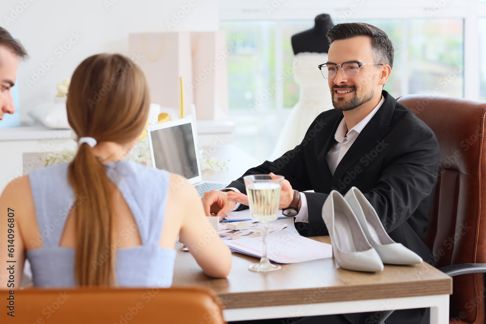 Male wedding planner working with couple in office