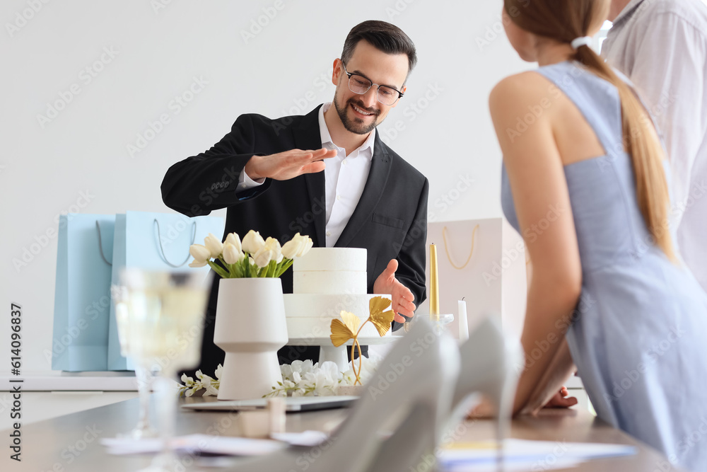 Male wedding planner working with couple in office