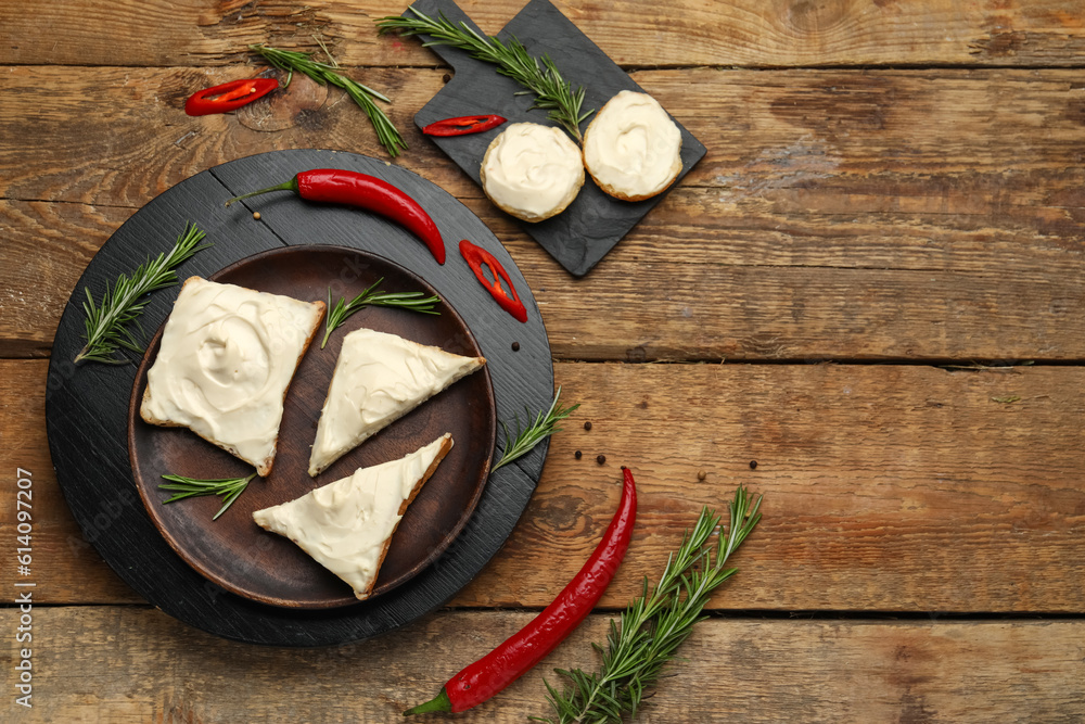 Tasty toasts with cream cheese on wooden background