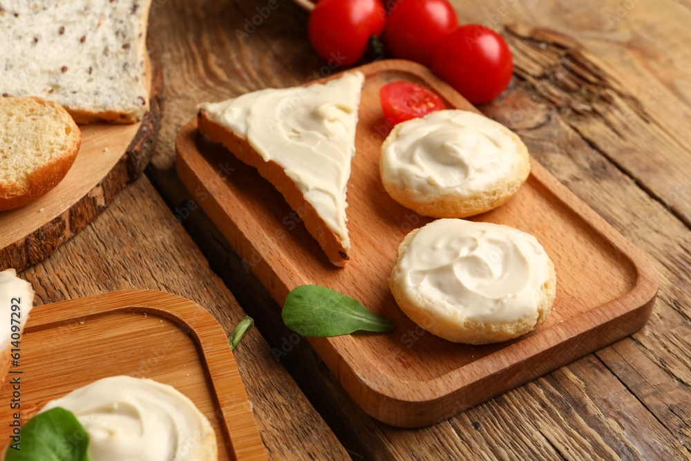 Board of tasty croutons and toast with cream cheese on wooden background