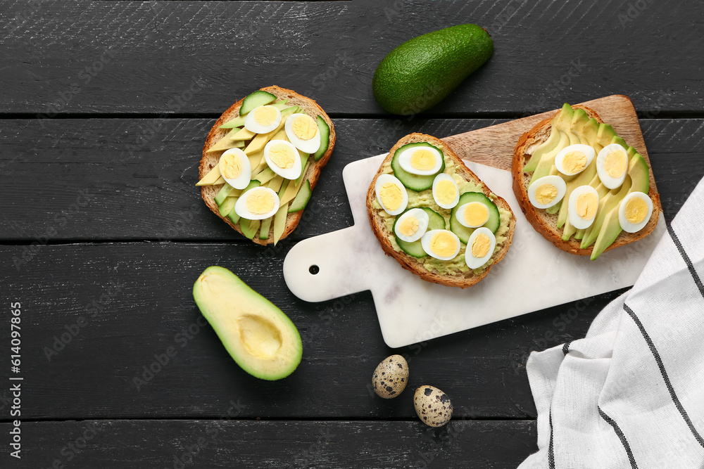 Tasty toasts with quail eggs, avocado and cucumber on dark wooden background