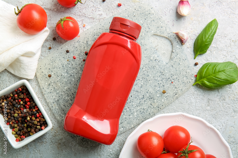 Board with bottle of ketchup and tomatoes on white background