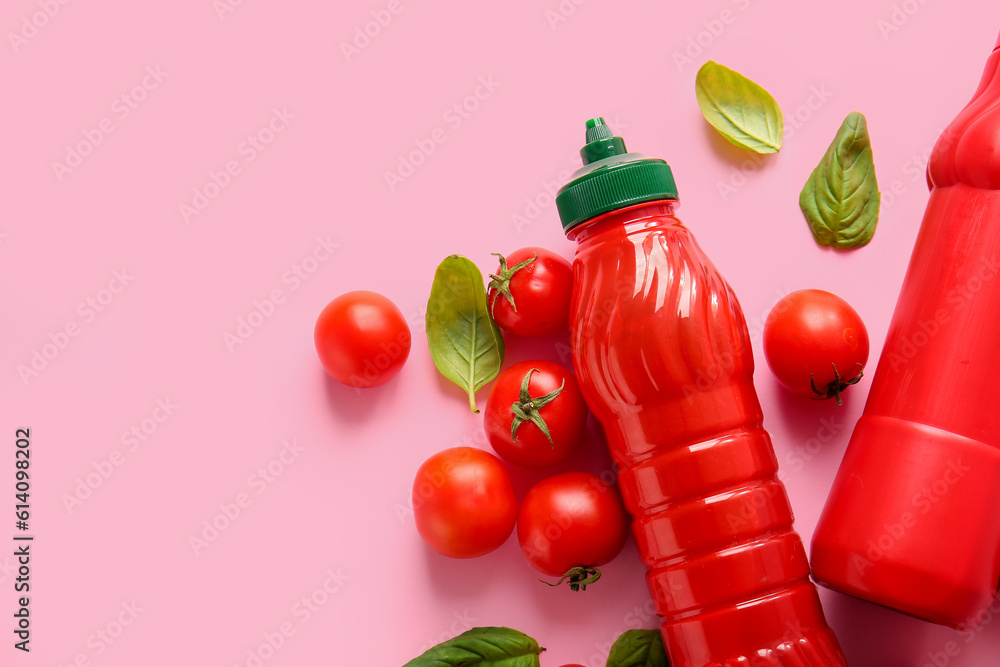 Bottles of ketchup and tomatoes on pink background