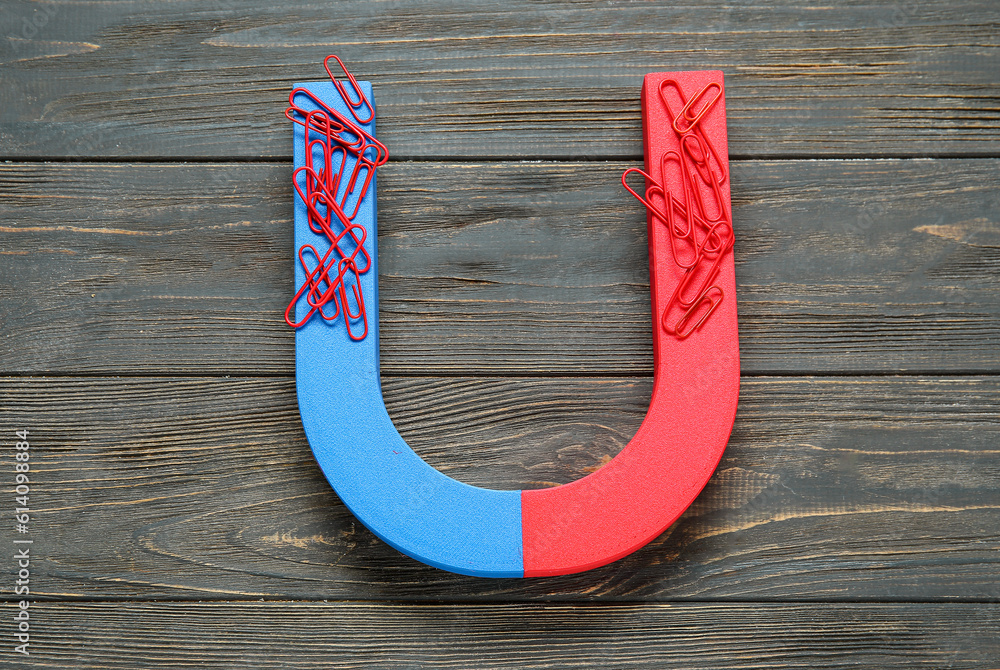 Magnet with paper clips on dark wooden background