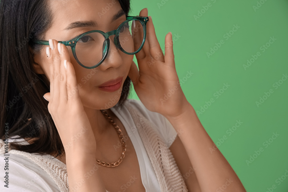 Beautiful Asian woman in stylish eyeglasses on green background, closeup