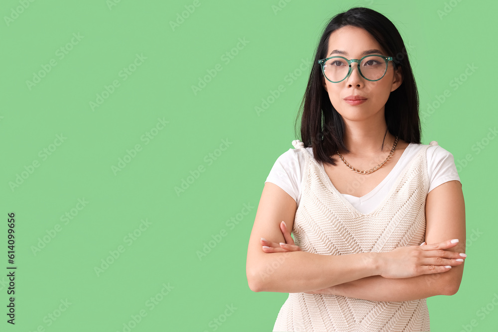 Beautiful Asian woman in stylish eyeglasses on green background