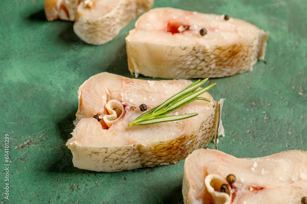 Pieces of raw codfish on green background