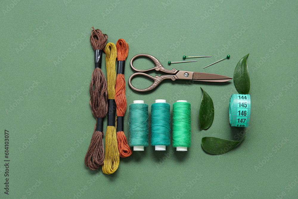 Set of different embroidery supplies on dark green background