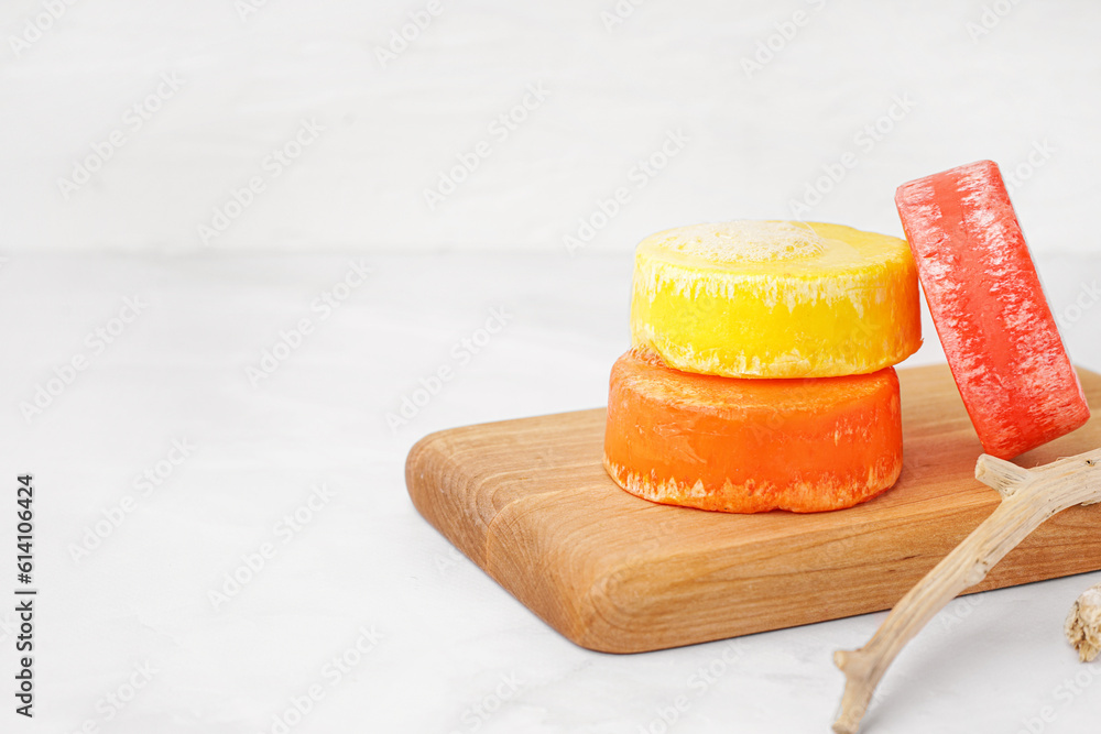 Board with different handmade solid shampoo and branches on light background, closeup