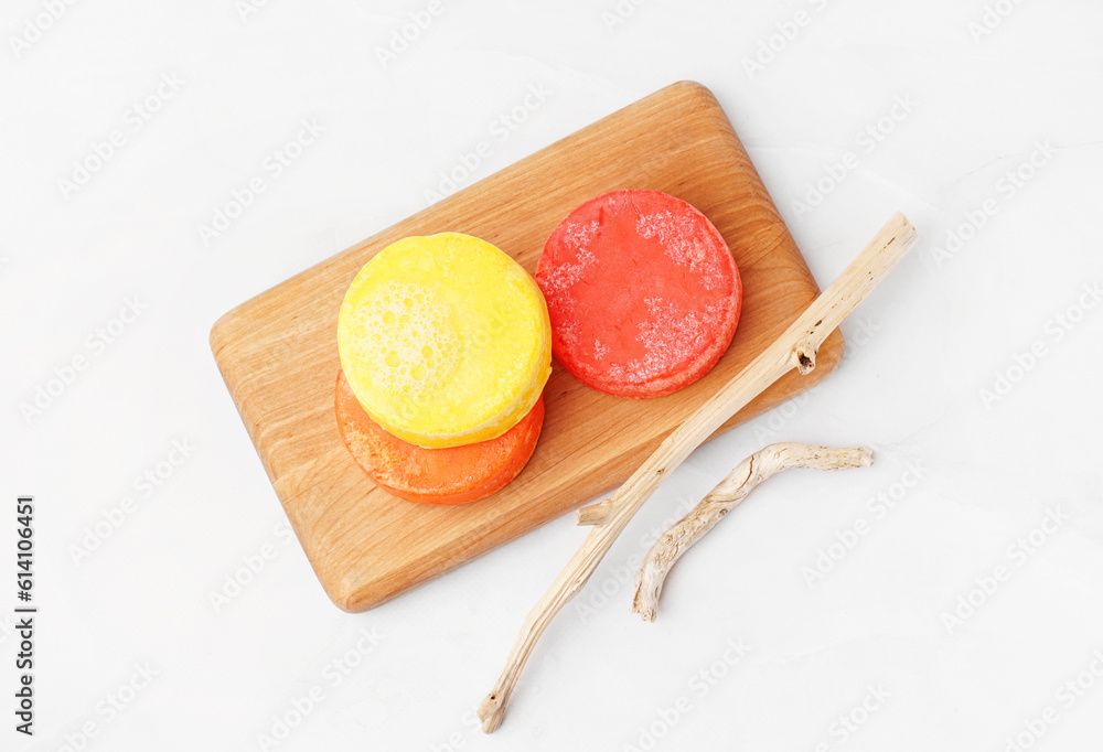 Board with different handmade solid shampoo and branches on light background