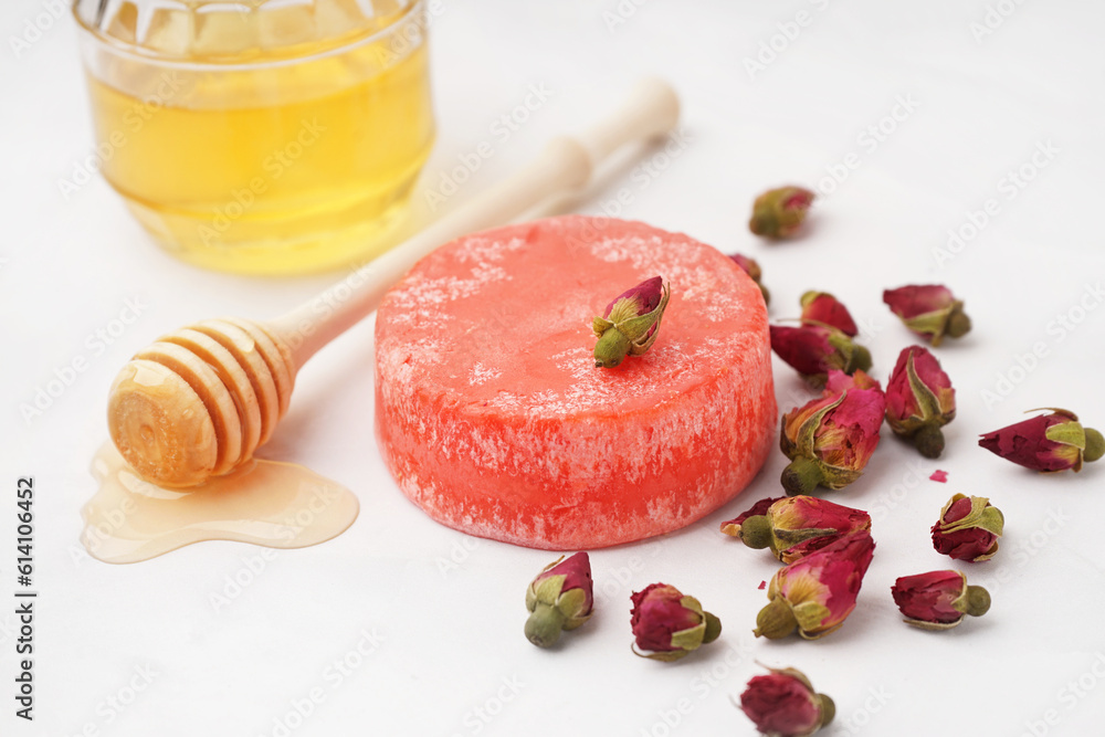 Handmade solid shampoo with honey and dry flowers on light background, closeup