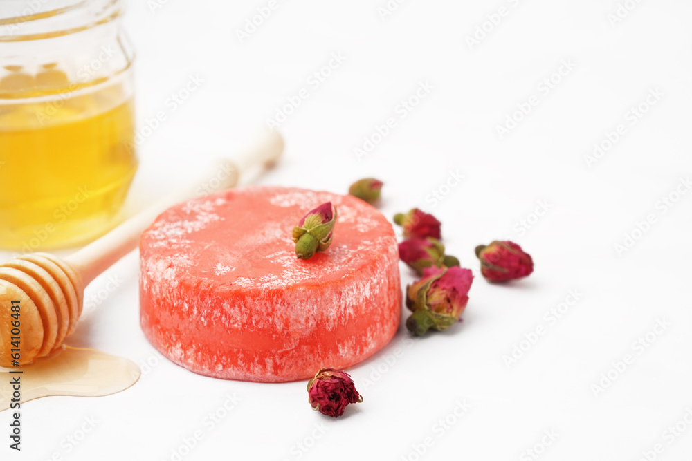 Handmade solid shampoo with honey and dry flowers on light background, closeup