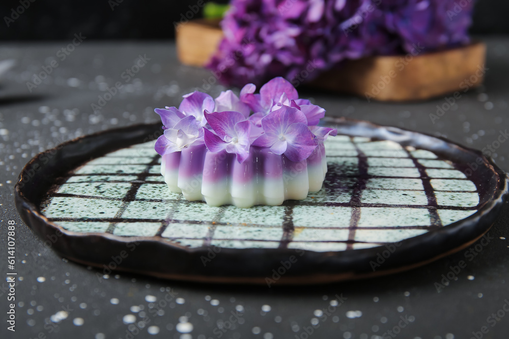 Plate of panna cotta with beautiful hydrangea flowers on black table