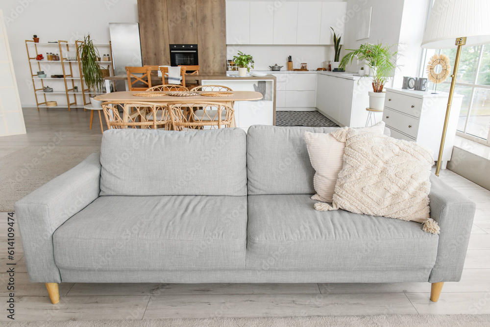 Interior of light open plan kitchen with grey sofa