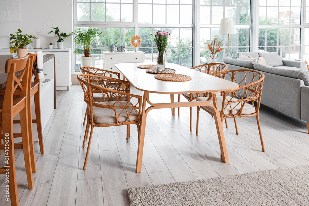 Interior of light open plan kitchen with dining table and grey sofa