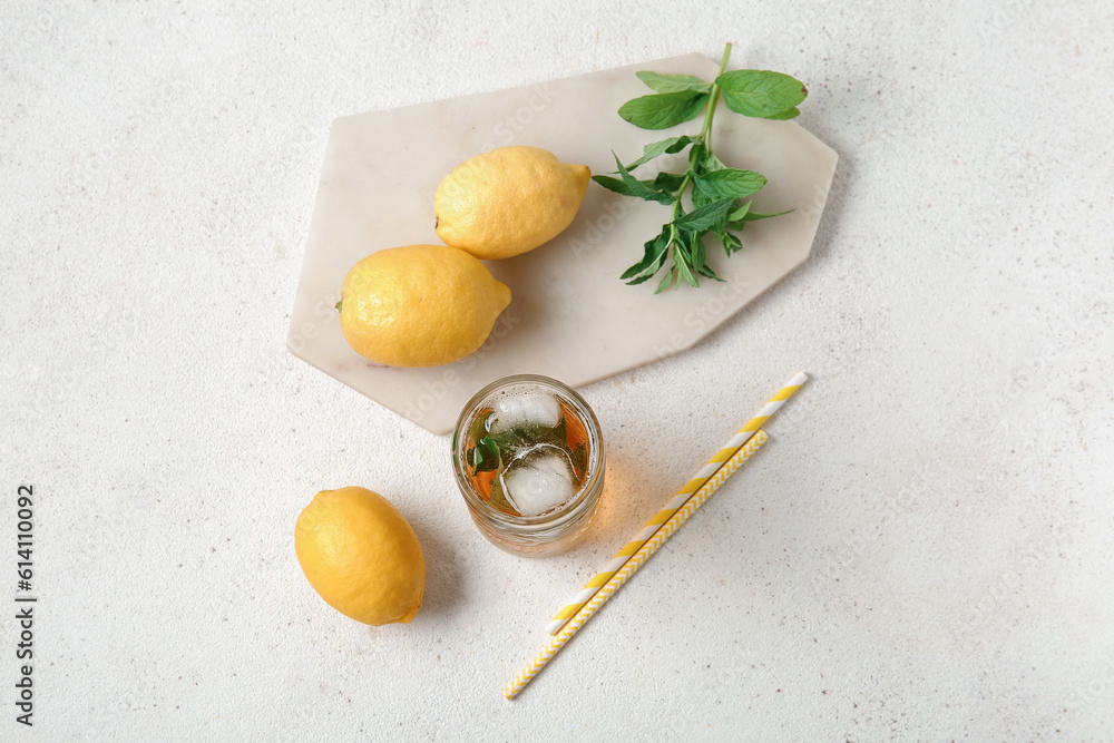 Glass of ice tea and board with lemons on white background