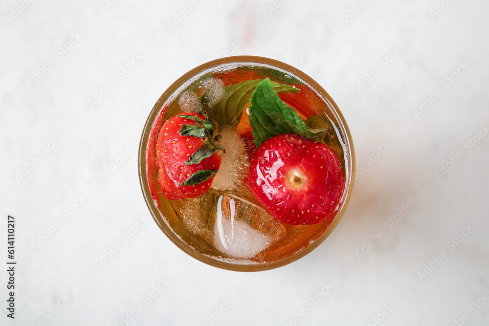 Glass of ice tea with strawberry and mint on white background