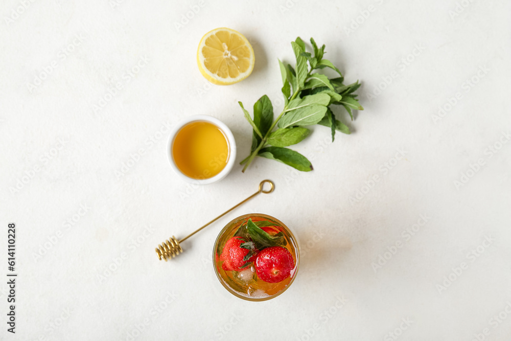 Glass of ice tea with strawberry and mint on white background