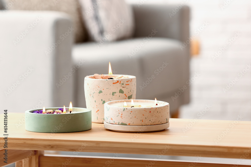 Holders with burning candles on table in room, closeup