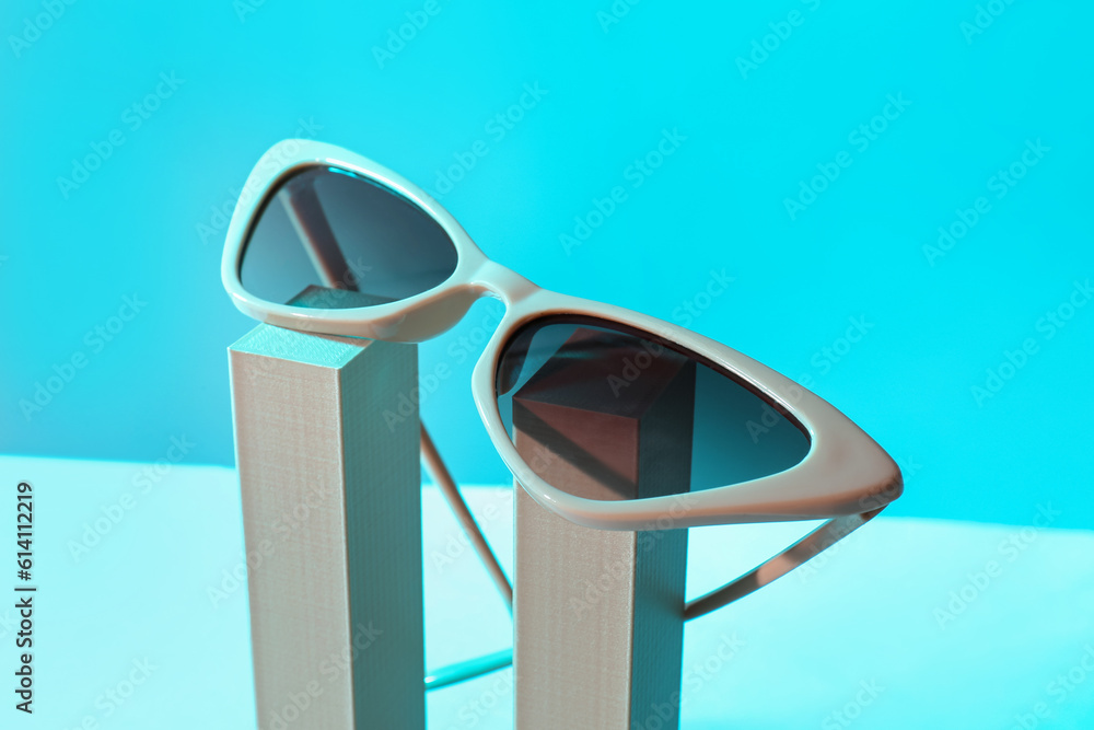 Podium with stylish sunglasses on blue background