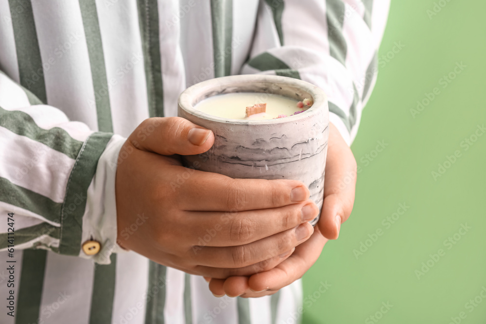 Woman holding candle on green background, closeup