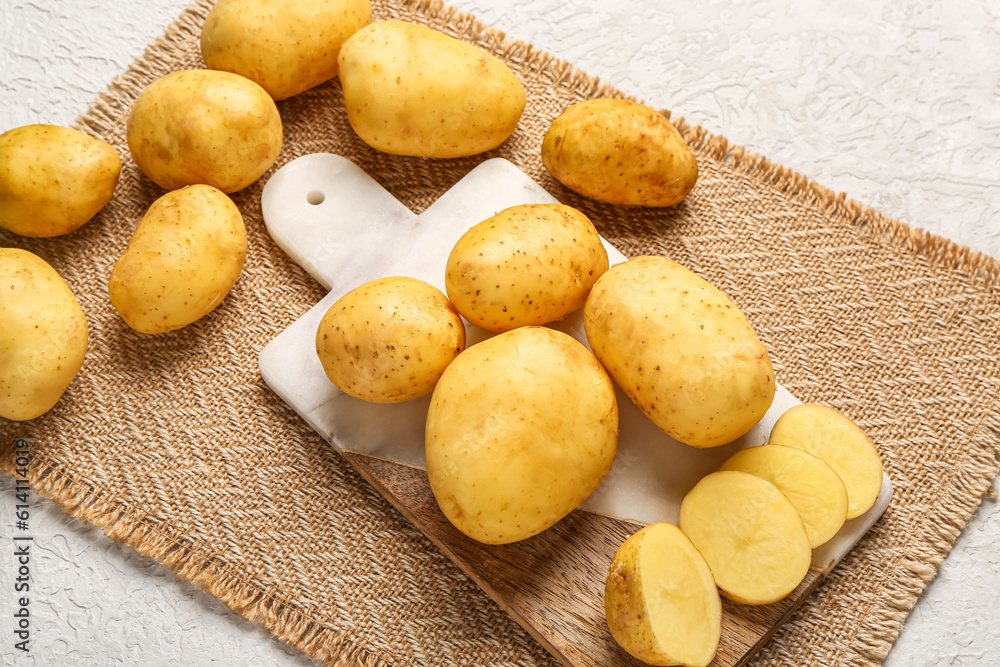 Board with raw baby potatoes and slices on white background