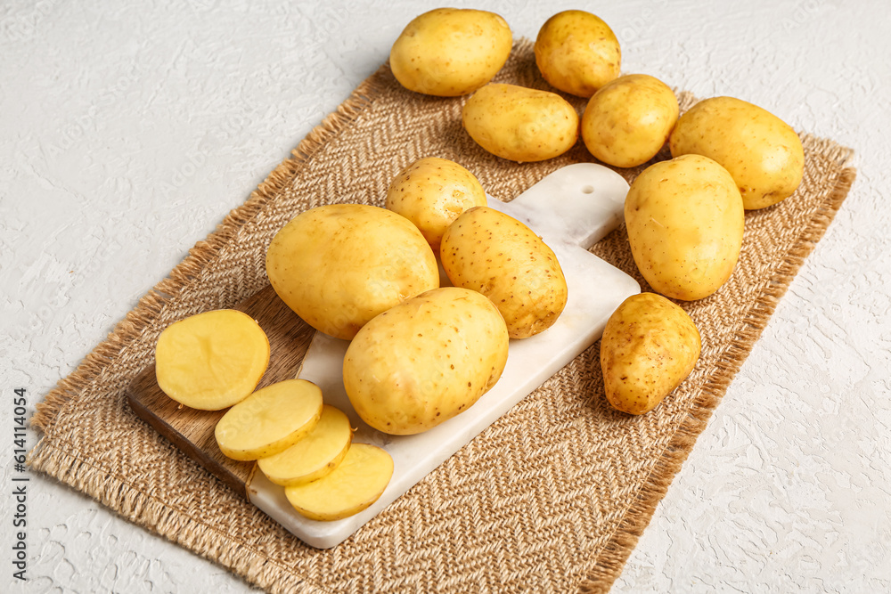 Board with raw baby potatoes and slices on white background