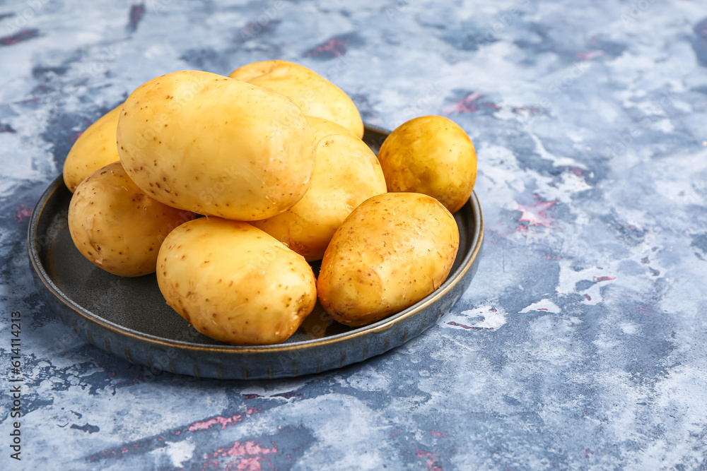 Tray with raw baby potatoes on blue background