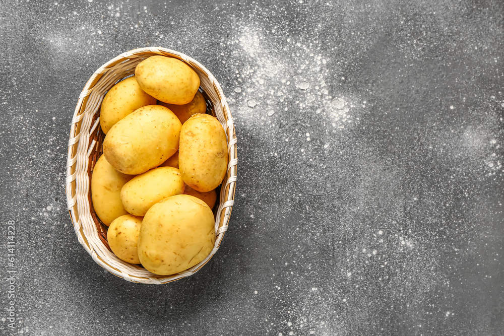 Wicker bowl with raw baby potatoes on grey background