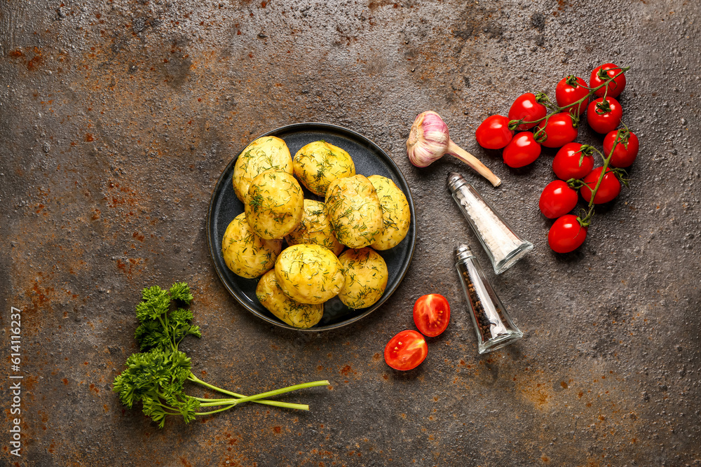 Plate of boiled baby potatoes with dill and tomatoes on dark background