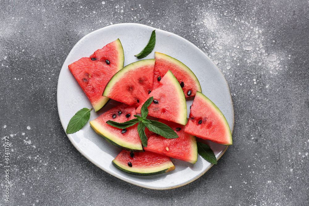 Plate with pieces of fresh watermelon and mint on grey background