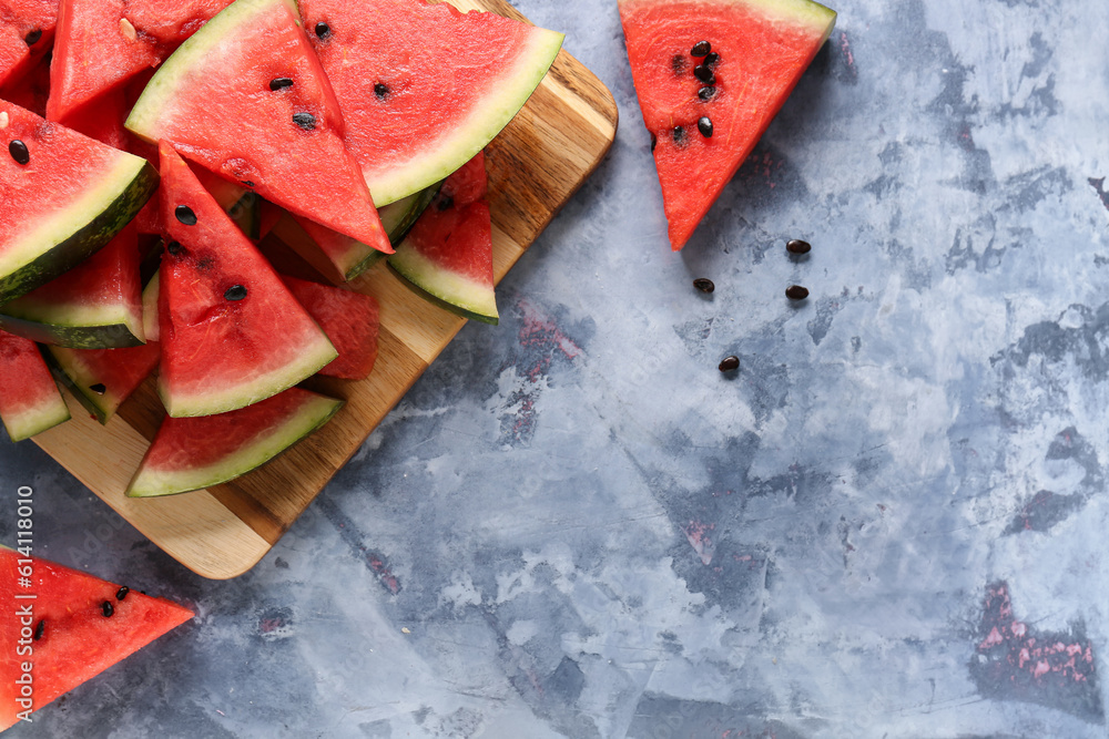 Board with pieces of fresh watermelon on blue background