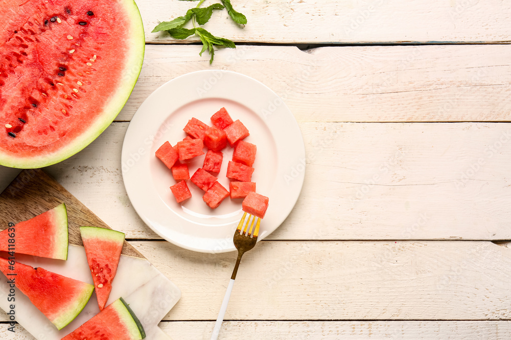 Plate and board with pieces of fresh watermelon on white wooden background