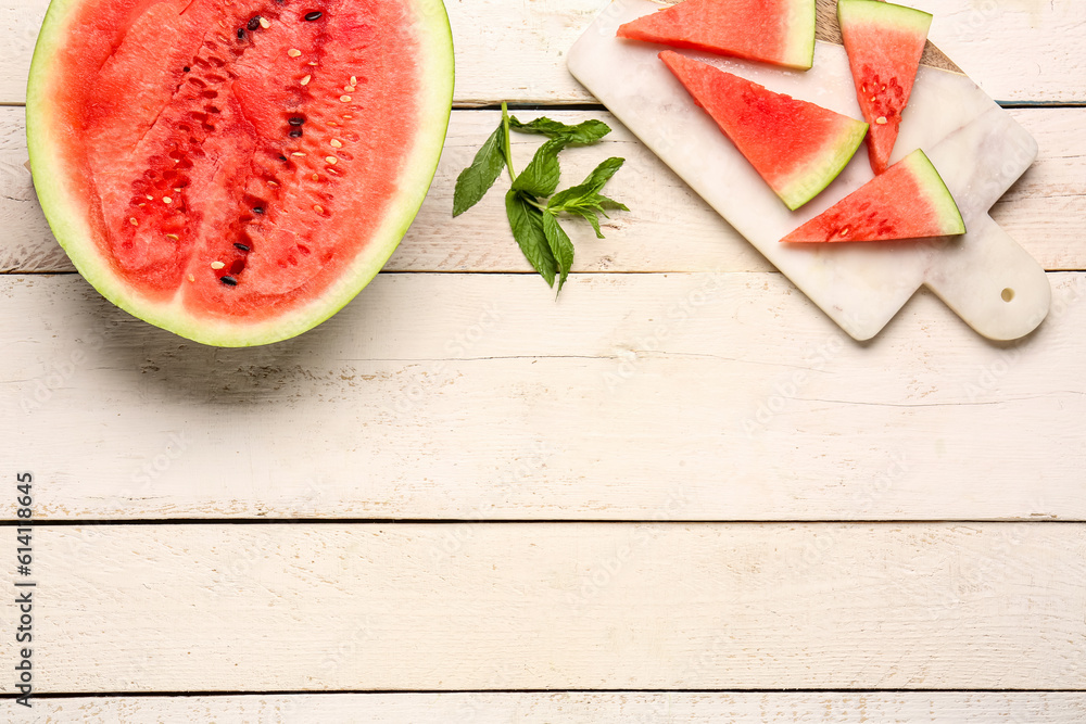 Half of fresh watermelon and board with pieces on white wooden background