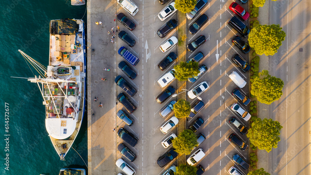 An aerial view of the parking lot with cars. Parking near the port. A docked ship. Photo from a dron