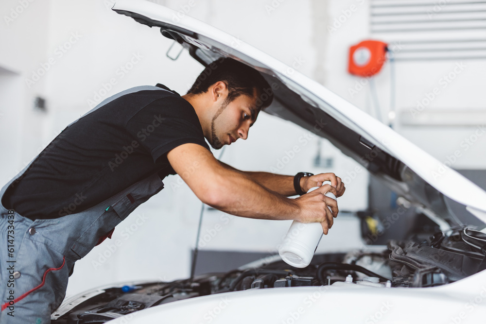 Car mechanic working in workshop checking engine