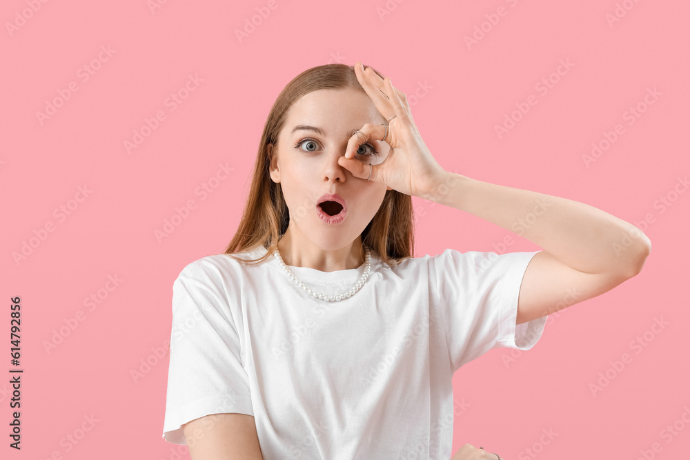 Funny young woman in t-shirt showing OK on pink background