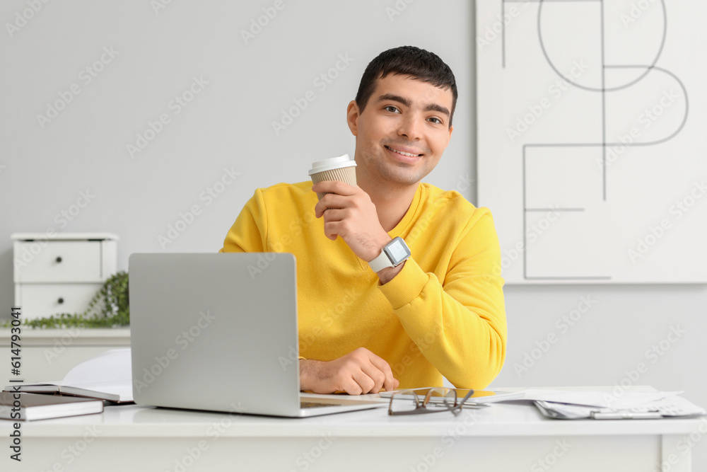 Young man drinking coffee at workplace