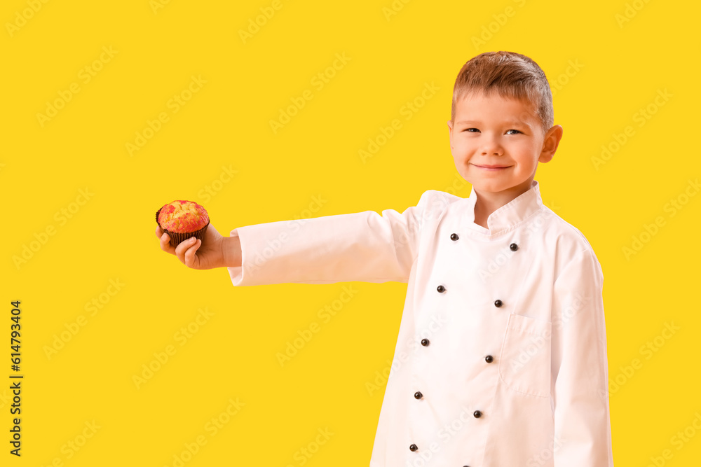 Cute little chef with tasty cupcake on yellow background