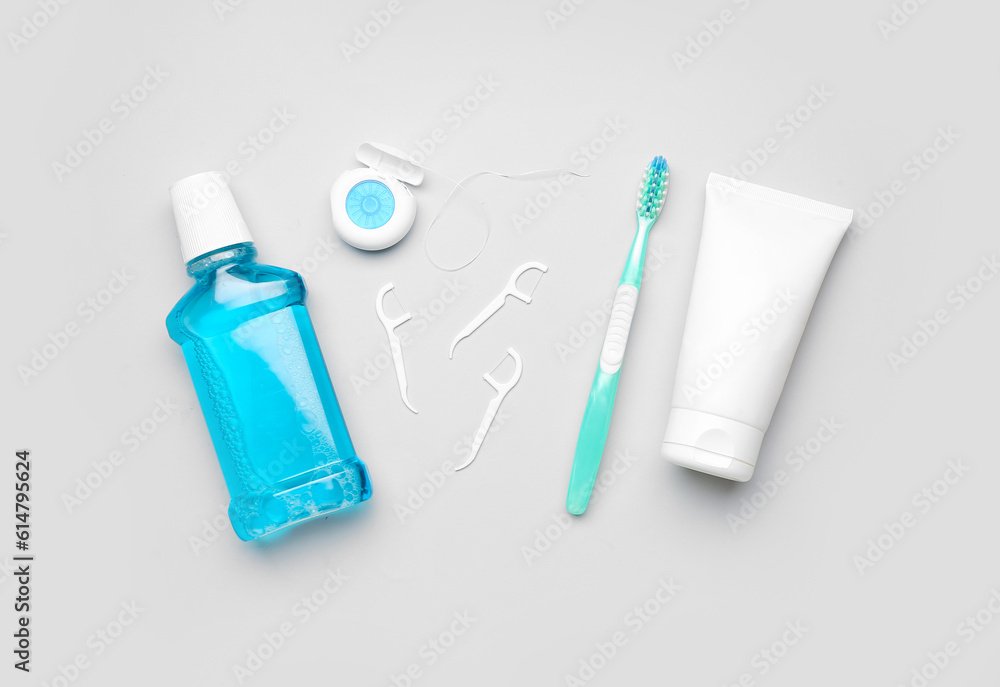 Rinse, dental floss, brush and tube of toothpaste on grey background