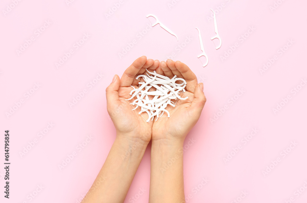 Woman holding many floss toothpicks on pink background