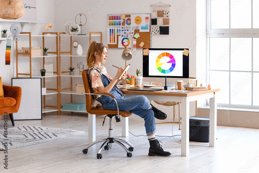 Female graphic designer working with notebook at table in office