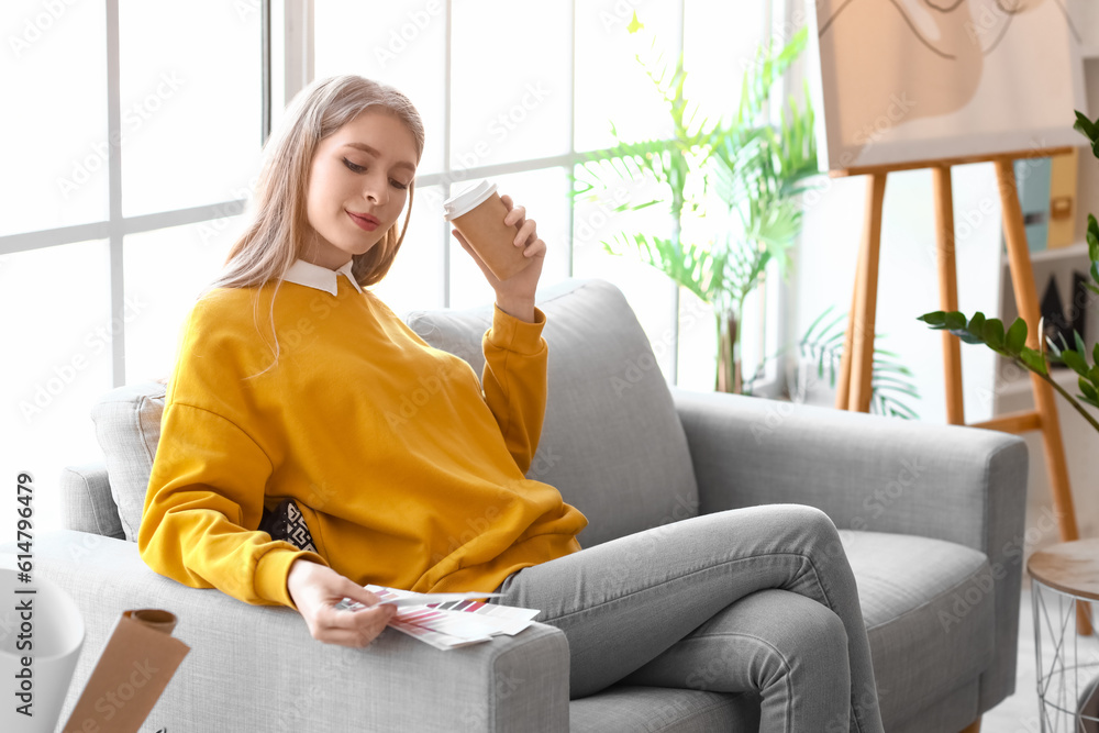 Female graphic designer with cup of coffee and color palettes in office