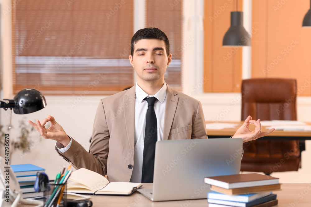 Young businessman meditating in office. Balance concept