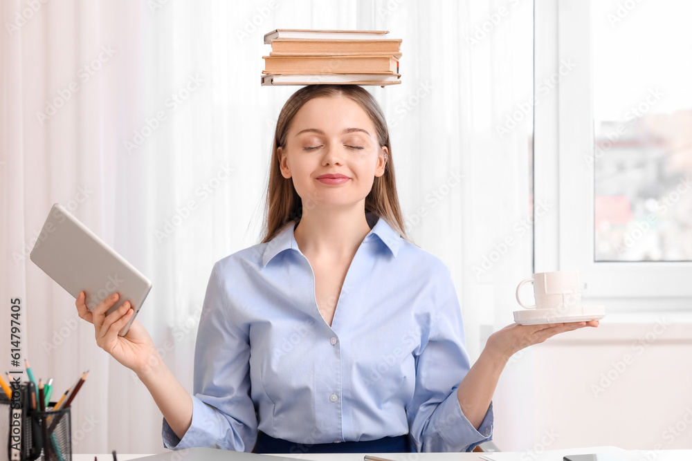 Young businesswoman with books, tablet computer and cup of coffee in office. Balance concept