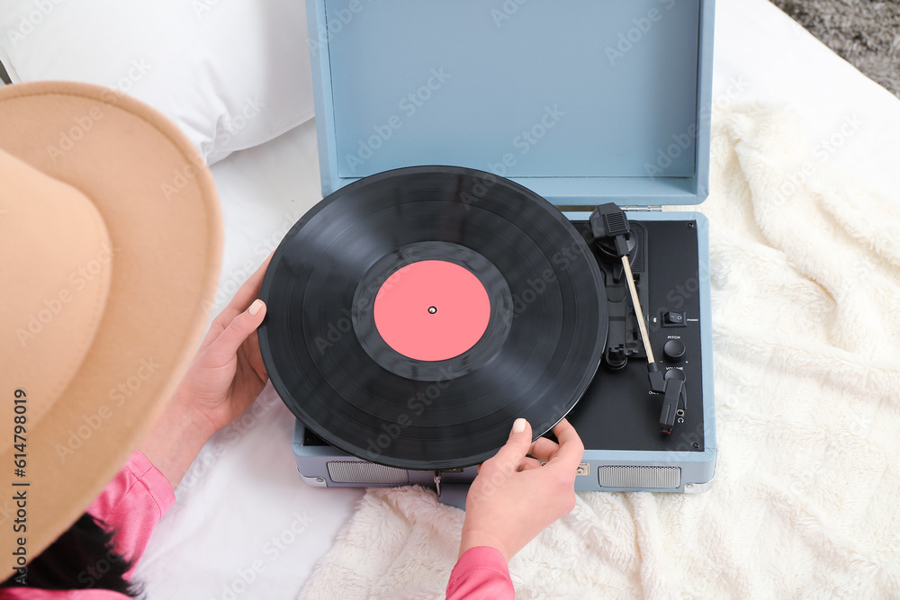 Young woman with vinyl disk and record player in bedroom, closeup