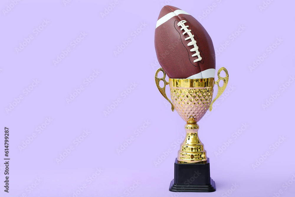 Gold cup with rugby ball on lilac background