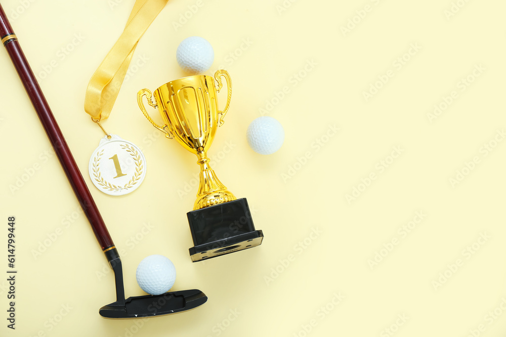 Gold cup with first place medal, golf club and balls on yellow background